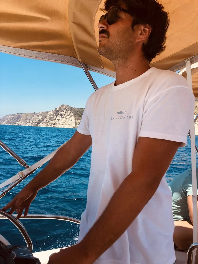 Charis at the wheel of SeaStories, the Kefalonia coastline behind him.